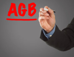 Male hand in business wear holding a thick pen, writing German term "AGB" (terms & conditions in Germany)