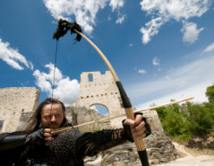 zielsicherer mittelalterlicher Bogenschütze vor Ruinen einer alt